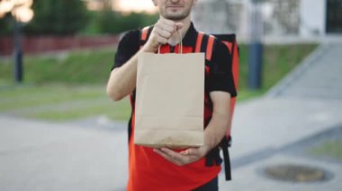 Restorandan yemek getiren adam sipariş etti. Tişörtlü ve şapkalı yakışıklı bir genç. Pakette gülen yiyeceklerle mutlu teslimatçılar. Kapıdan kapıya servis servisi.