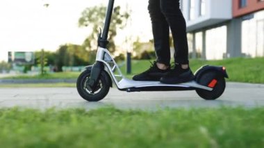 Siyah spor ayakkabılı adam elektrikli mobiletle geziyor. Modern Adam Güneşli Gün 'de elektrikli scooter kullanıyor. İşe elektrikli scooterla giden yetişkin bir adam. Çevre dostu ulaşım