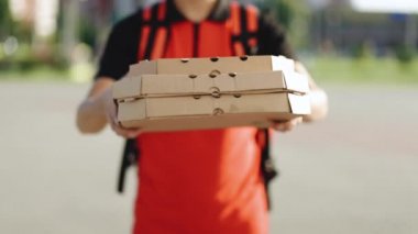 Kuryelerin ellerine ve pizzalarına yakın çekim. Karton pizza kutusunu şehre karşı taşıyan teslimatçının portresi, kurye yemek teslimatı. Teslimatçı elinde sıcak pizzayla kutular tutuyor, internetten yemek sipariş ediyor.