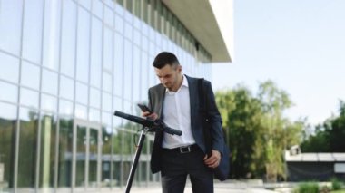 İşadamı e-scooterına doğru yürüyor. Turist park alanında elektrikli scooter kullanıyor. Çevre dostu ulaşım. Yetişkin bir adam işe elektrikli scooterla gidiyor.