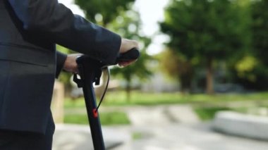 Kafkasyalı işadamı modern ofis binasının yakınında elektrikli scooter kullanıyor. Başarılı yetişkin erkek girişimci ekolojik taşımacılıkla işe gidiyor. Sağlık, başarı, iş