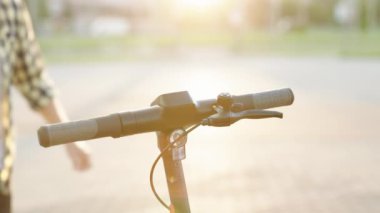 Adam e-scooterına doğru yürüyor. Turist park alanında elektrikli scooter kullanıyor. Çevre dostu ulaşım. Yetişkin bir adam işe elektrikli scooterla gidiyor.