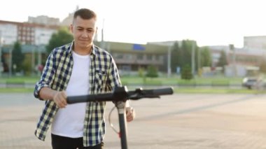 Adam e-scooterına doğru yürüyor. Turist adam elektrikli scooter kullanıyor. Yetişkin bir adam elektrikli scooter kullanıyor. Sabahları sokakta scooter 'la gezen yakışıklı bir adam. Çevre dostu ulaşım