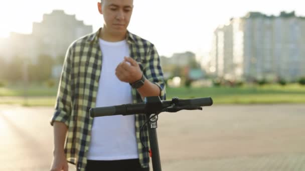 Homme hipster méconnaissable prendre louer scooter électrique kick NFC casier sans contact sur vélo avec application de montre intelligente dans le partage de stationnement. Partager l'éco-transport d'affaires en ville — Video
