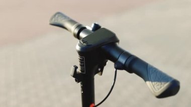 Hippi adam elektrikli scooter 'ı çalıştırıyor. Erkek, modern aletin başlama düğmesine basıyor ve şehir caddesi boyunca araba sürüyor. Yakından genç bir adamın elleri. Ekolojik alternatif ulaşım