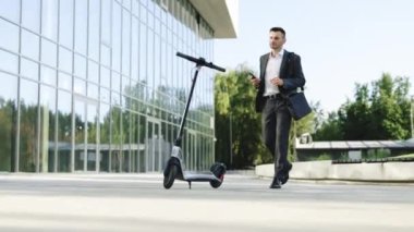 Telefonu ve elektrikli scooter 'ı olan genç ve şık bir iş adamı. İş adamı cep telefonu uygulaması kullanarak elektrikli scooter kiralıyor. Ekolojik ulaşım. Çevre dostu ulaşım
