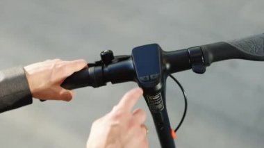 Tanınmayan kişi elektrikli scooter 'ı çalıştırıyor. Adam elektrikli scooter 'ı çalıştırıyor, direksiyona yakın çekim yapıyor. Yakından genç bir adamın elleri. Bir adam onun elektrikli scooterını tutuyor.