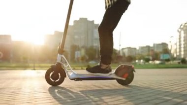 E-scooter binicisi, insan binicisi paylaşımı ya da kişisel çevre taşımacılığı. Erkek hippi, modern yöntemle işe elektrikli scooter ile gidiyor. Hızlı sürüş elektrikli taşıma, sabah ışığı