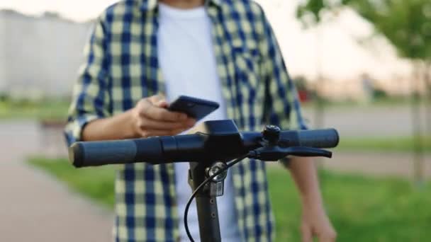 Telefonansökan för hyra skoter. Närbild av hands man med smart telefon. Turist med e-scooter eller cykel. Ekologisk stadstransport. E-scooter ryttare hyr personlig ekotransport — Stockvideo