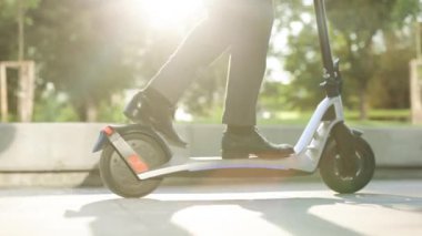 Şehirde elektrikli scooter kullanan takım elbiseli adam. Bilinmeyen iş adamı klasik takım elbiseli, elektrikli mobiletle geziyor. Modern çevre dostu ulaşım. Hızlı sürüş elektrikli taşıma