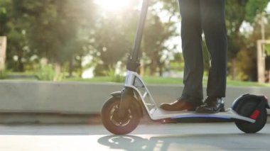 Bilinmeyen iş adamı klasik takım elbiseli, elektrikli mobiletle geziyor. Şehirde elektrikli scooter kullanan takım elbiseli adam. Modern çevre dostu ulaşım. Hızlı sürüş elektrikli taşıma