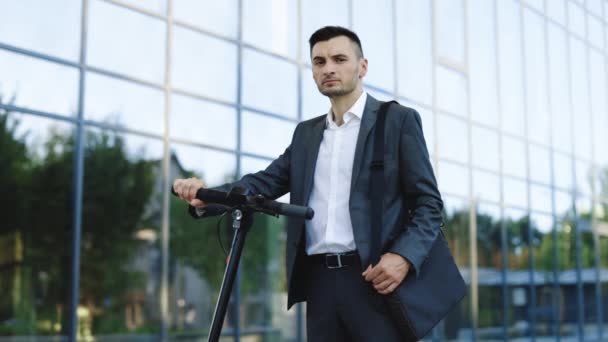 Ritratto di uomo d'affari sicuro in piedi con scooter elettrico e guardando la fotocamera. E-Scooter pilota noleggio personale eco trasporto. Trasporto urbano alternativo moderno. Stylysh uomo sul veicolo all'aperto — Video Stock