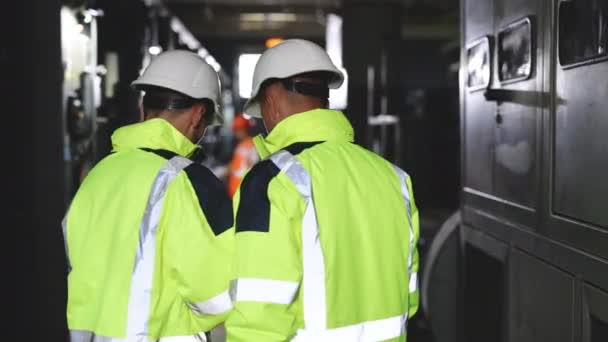 Vista posterior de dos ingenieros de pie en la central eléctrica, utilice la computadora de la tableta digital, tienen discusión. Concepto de industria de tecnología empresarial energética. — Vídeos de Stock