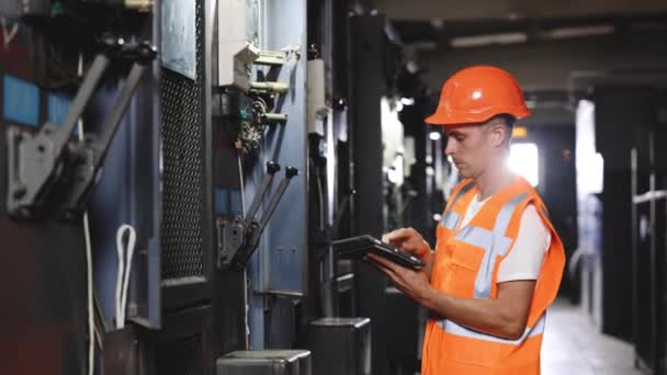 Ingenieur man werkt in de fabriek. Elektrotechnicus met behulp van digitale tablet inspecteren en programma voor elektrische energiesystemen in de elektrische controlekamer. Begrip industrie, fabriek, hernieuwbare energie — Stockvideo