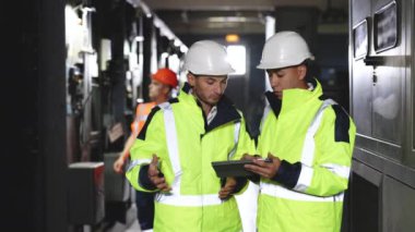 Hard Hats 'taki Erkek Elektrik Mühendisleri Tablet Bilgisayar Kullanırken Yeni Projeyi Tartışıyor. Hesaplanmış Mühendislik Kararları veriyorlar. Elektrik Fabrikası 'nda çalışıyorlar.