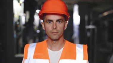 Güvenlik kaskı takmış, yüzü kir içinde neşeli ustabaşı portresi. İnşaat inşaatı sırasında inşaat alanında duran kameraya bakın..