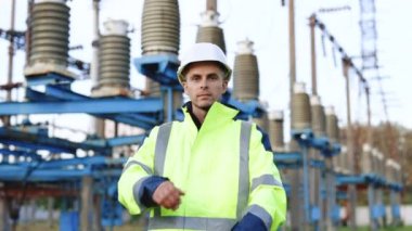 Elektrik santralindeki sanayi işçisinin portresi. Kameraya bakarken kollarını kavuşturan koruyucu kasklı mutlu erkek mühendisin portresi.