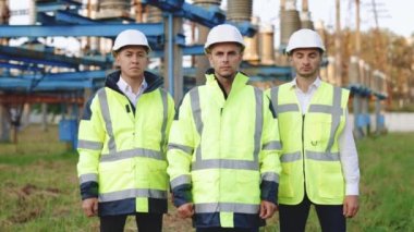 Kameranın önünde, güvenlik ekipmanlarıyla birlikte güçlü bir ekip gibi poz veren çeşitli uzman mühendislerin portresi.