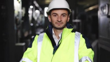 Elektrik kontrol odasında çelik yelek giyen genç bir fabrika mühendisi ya da işçi portresi yakın plan. Endüstri ve mühendislik kavramı