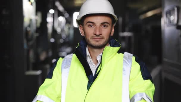 電気制御室で安全ベストとハード帽子交差腕を身に着けている若い工場のエンジニアや労働者の肖像画を閉じます。産業工学の概念 — ストック動画
