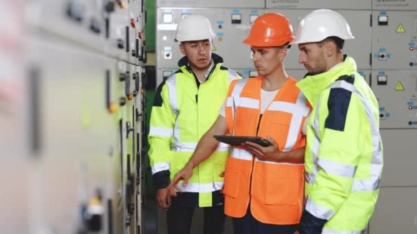 Inżynier pokazuje męskich inspektorów z tabletem zainstalowanym w nowoczesnej elektrowni wiatrowej. Technik skontrolować do kontroli systemu ekranu panelu do wytwarzania energii elektrycznej z fabryki — Wideo stockowe