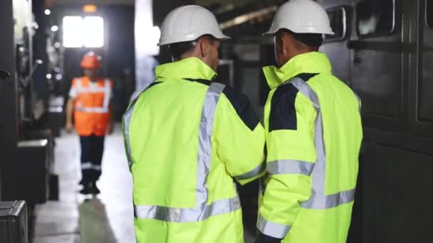 Back View of Two Engineers Stand in Electric Power Station, Use Digital Tablet Computer, Have Discussion (англійською). Індустрія енергетики. — стокове відео