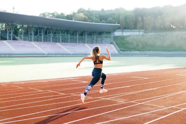 Beyaz kadın spor kıyafetleriyle koşuyor stadyumun spor pistinde kardiyo çalışması yapıyor. Yetişkin bayan atlet koşu, maratondan önce antrenman. Sağlığa. Sporcu Kadın.