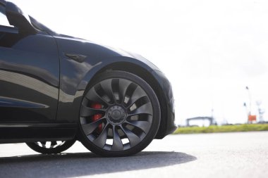 Lviv, Ukrayna - 16 Ekim 2025: Siyah Tesla Model 3 ön tekerlek yakın. Tesla şehre park etmiş, yan manzaralı. Tekerlekler, frenler, araba lastikleri. Tesla, Elon Musk 'a ait bir elektrikli otomobil şirketi.