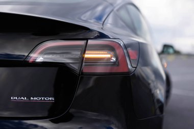 Lviv, Ukrayna - 16 Ekim 2025: Arka farlar elektrikli Tesla Model 3 Performans arabası, otomotiv endüstrisi. Yanıp sönen sinyal doğru yönü gösteriyor. Sarı kuyruklu araba yolda.