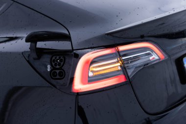 Hızlı şarj eden soket tip 2 kombinasyon elektrikli araba. DC - EV vagonunda tip 2 EV şarj edicisi. Elektrikli aracın 2. tip CCS prizi. Araba yolda kuyruk sarı ışıkta.