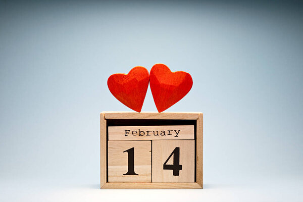 Love symbol tiny red hearts on wooden blocks calendar. February 14 Valentines Day
