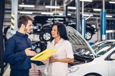 Otomobil tamirhanesi. Tamirci müşteriyle iletişim kurar.