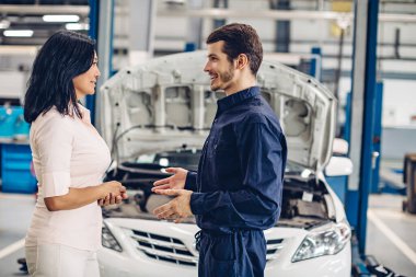 Otomobil tamirhanesi. Tamirci müşteriyle iletişim kurar.