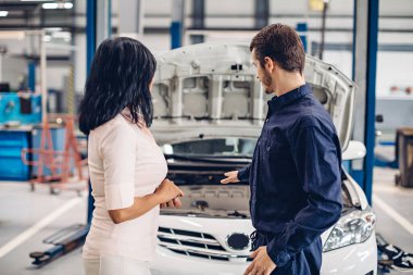 Otomobil tamirhanesi. Tamirci müşteriyle iletişim kurar.