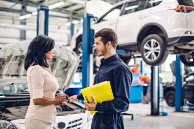 Otomobil tamirhanesi. Tamirci müşteriyle iletişim kurar.