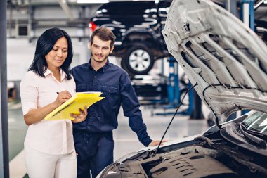 Otomobil tamirhanesi. Tamirci müşteriyle iletişim kurar.