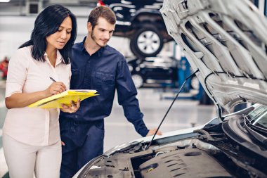 Otomobil tamirhanesi. Tamirci müşteriyle iletişim kurar.