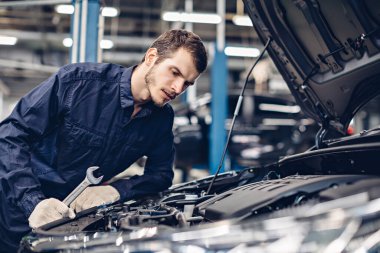 Otomobil tamirhanesi. Tamirci araba motorunu inceliyor.