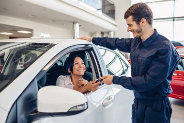 Araba servisi merkezi sahnesi. Tamirci müşteriye araba anahtarı verir