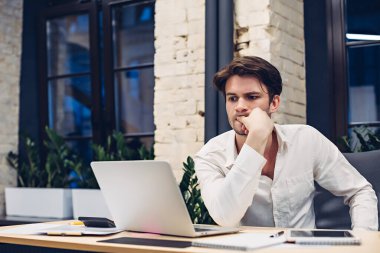 Ofiste dizüstü bilgisayarla çalışan düşünceli bir iş adamı.