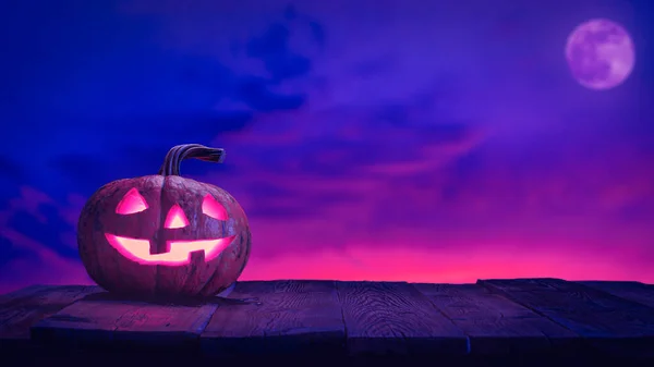 Halloween calabaza jack o linterna en tablones de madera contra el cielo rosa y azul con la luna Imágenes de stock libres de derechos