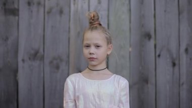 Kameraya ve bir şey hakkında rüyalar görünümlü pembe parlak elbiseli düşünceli kız