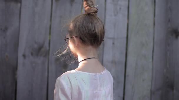 Vue de l'arrière : Adolescente debout et réfléchissant à quelque chose aux rayons d'été et au vent léger — Video