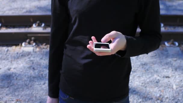 Hombre escribiendo en el teléfono en el fondo del ferrocarril — Vídeos de Stock