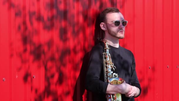 Portret van een saxofonist op een rode muur — Stockvideo