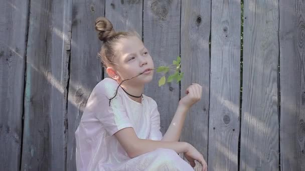 Chica sosteniendo una flor en su boca y soñando mirando al cielo — Vídeo de stock