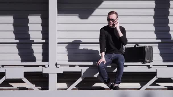 Man aan het praten over de telefoon busstation — Stockvideo