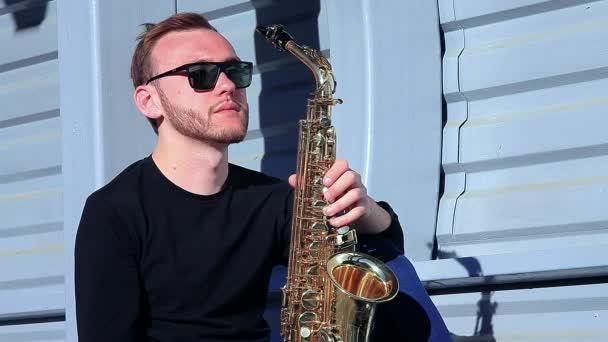 Saxofonista con gafas de sol sosteniendo un saxofón — Vídeo de stock