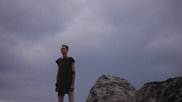 Um homem do futuro está no topo de uma montanha e olha para a distância — Vídeo de Stock