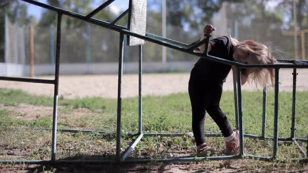 Schönes kleines Mädchen im schwarzen Anzug, das in einer Sportkonstruktion steht und sich zur Seite lehnt — Stockvideo
